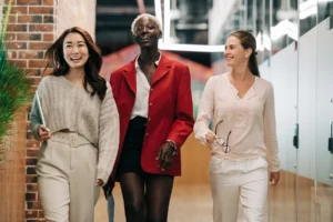 Three women in business attire walk confidently down a hallway.