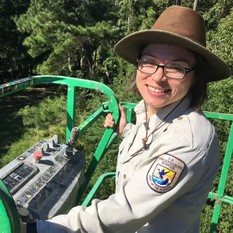 Nancy smiling, wearing a hat, in a tractor bucket